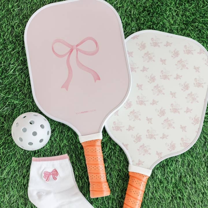 Two pickleball paddles with decorative designs on a grass surface