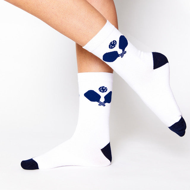 A pair of white crew socks with a blue and navy pickleball graphic on the ankle area.