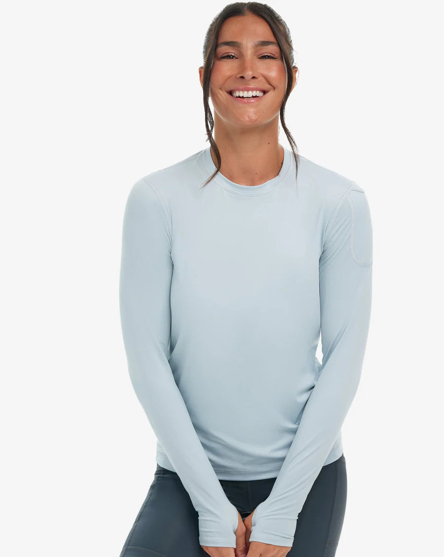 A woman wearing a long sleeve grey sun shirt with a left shoulder pocket, displaying the front view of the shirt.
