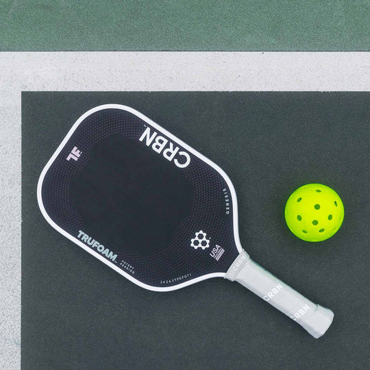 A black and green CRBN Tru Foam Genesis Hybrid 14mm paddle with a foam core, alongside a black carrying case. The paddle features geometric patterns and branding details in white and green colors.