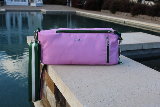 Purple bag with a green strap on a ledge by a pool