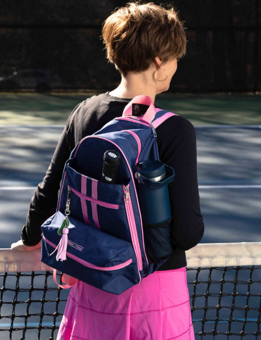Person with a blue and pink backpack on a tennis court