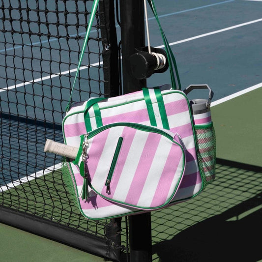 Pink and green striped bag hanging on a tennis racket against a tennis court background