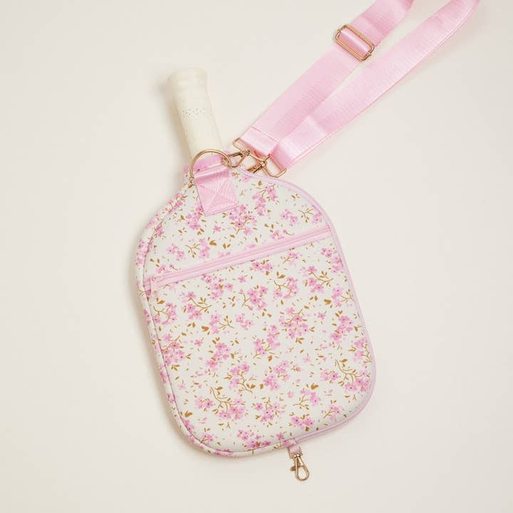 Floral-patterned bag with a pink strap on a light beige background
