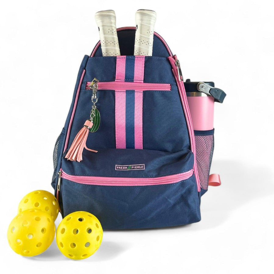 Navy backpack with pink straps, pickleball paddles, and balls on a white background
