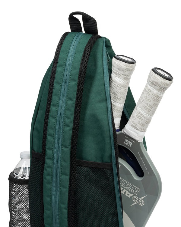 Green backpack with pickleball paddles and a bottle inside