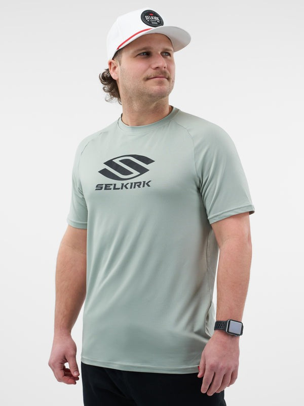 Man wearing a light gray t-shirt with Selkirk logo and a white cap on a light gray background