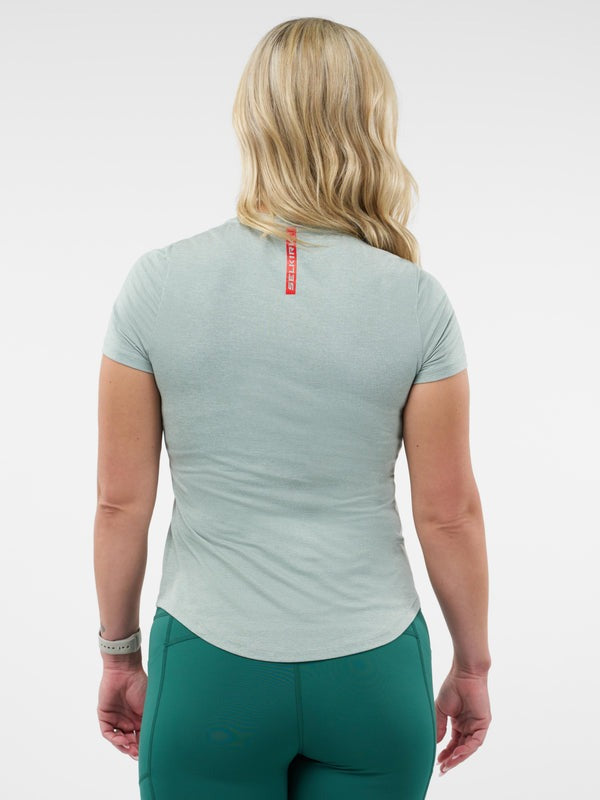 Person wearing a light green athletic shirt and teal leggings on a white background