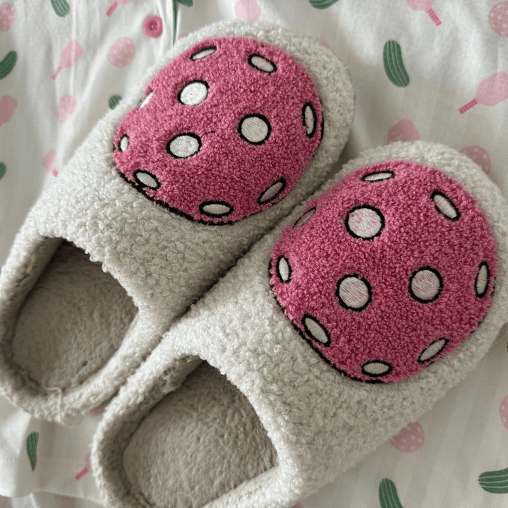 Pair of slippers with pink polka dot tops on a patterned background