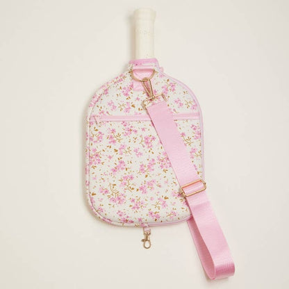 Floral-patterned sling bag with pink strap on a light beige background
