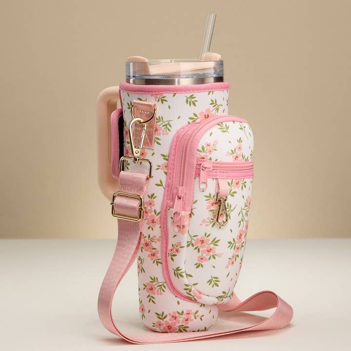 Floral-patterned tumbler holder with pink strap on a beige background