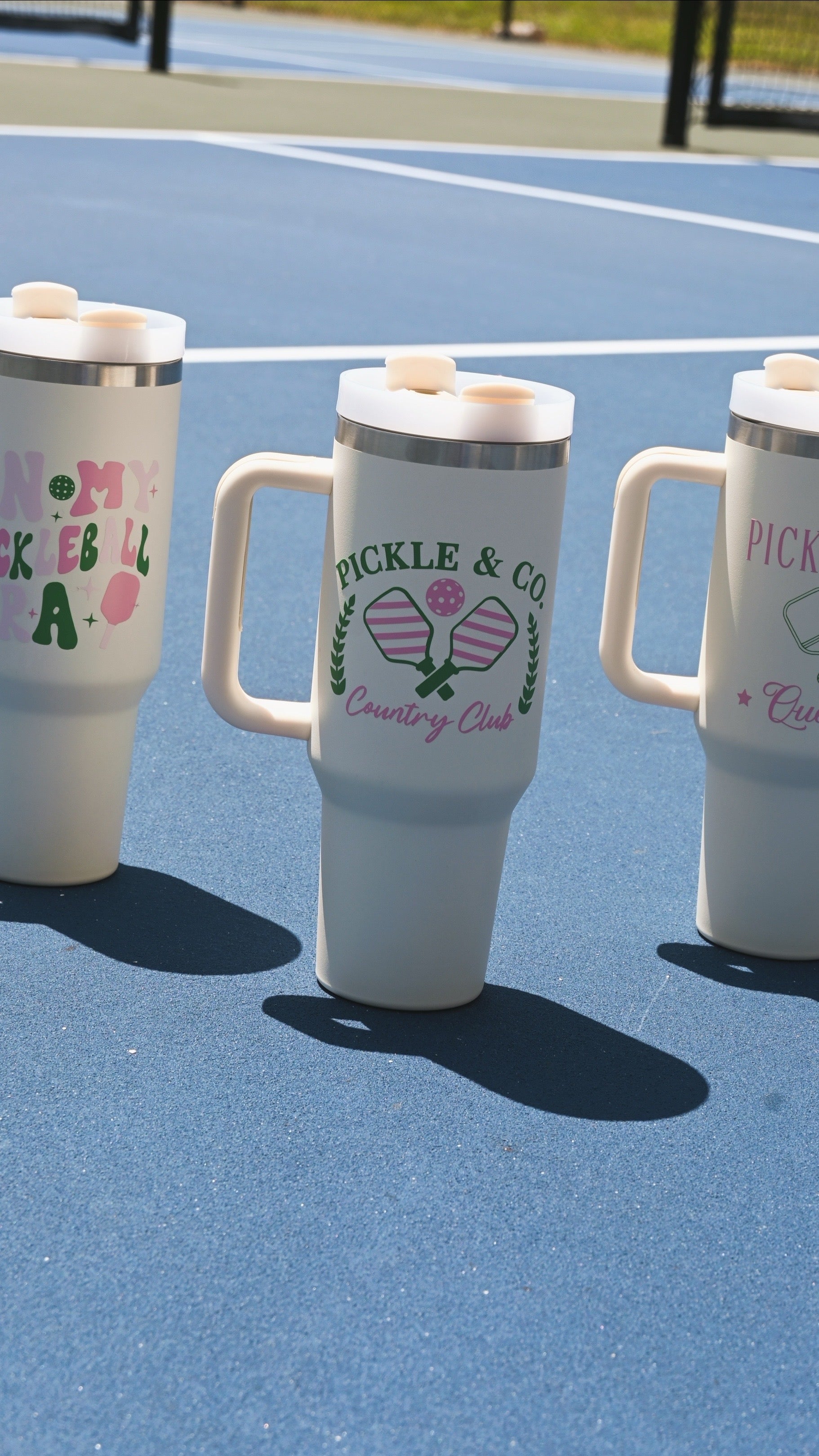Three white tumblers with decorative text and graphics on a blue surface