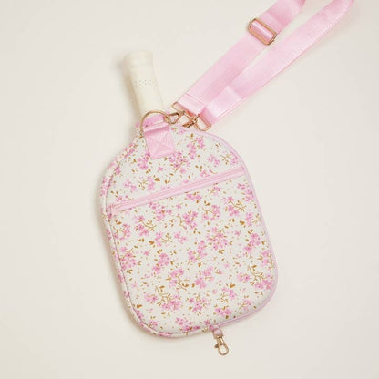 Floral-patterned bag with a pink strap on a light beige background
