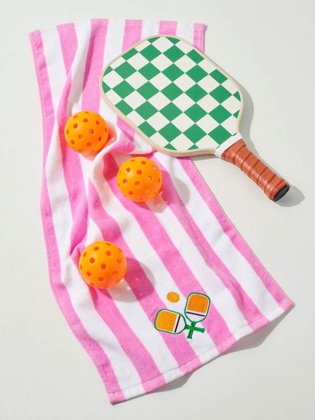 Checkered paddle and orange balls on a pink and white striped towel