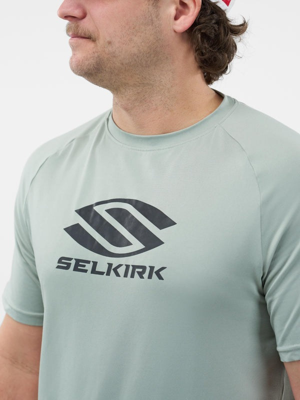 Person wearing a light gray t-shirt with Selkirk logo on a white background