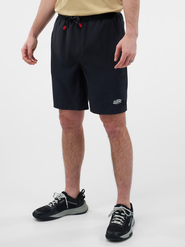 Person wearing black shorts with a logo on a white background